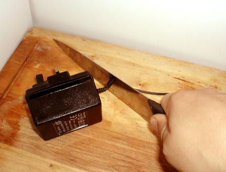 A knife blade cutting the cable of a generic charger/adaptor